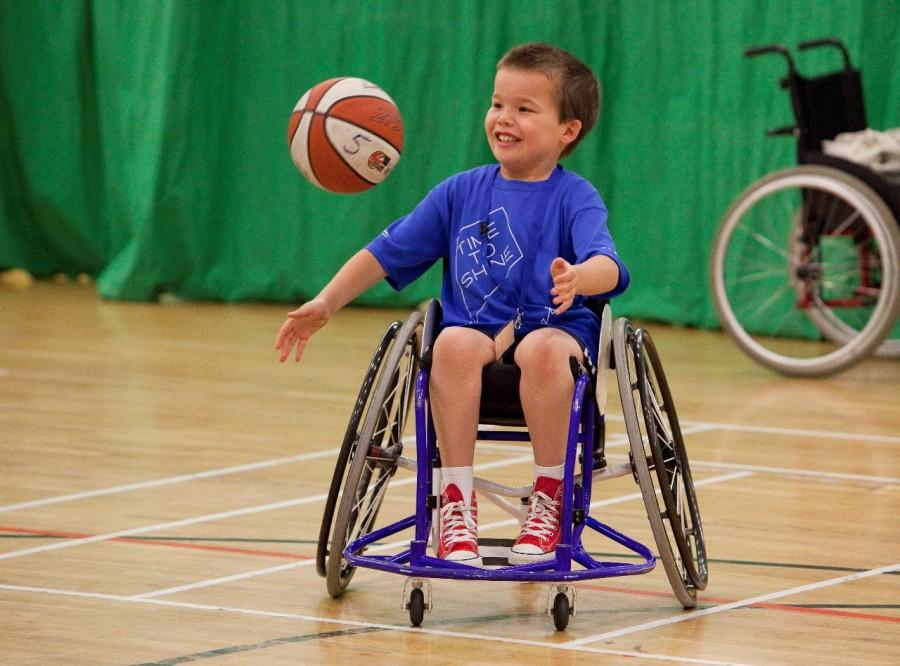 Kids with disabilities play adapted sports like this kid playing basketball. 