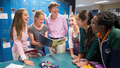 A few middle school students reading a book with Mrs. Fulcher