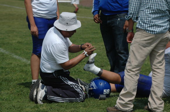 Players ankle being taped on the field in hopes of supporting the injured ankle.
