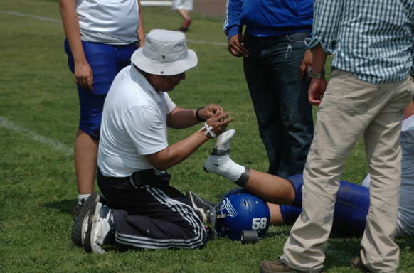 Player's ankle being taped on the field in hopes of supporting the injured ankle.