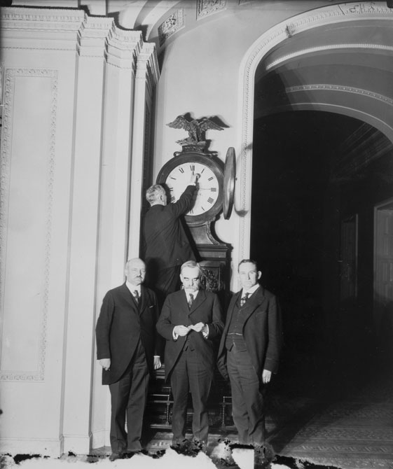 Senate Sergeant at Arms Charles P. Higgins turns forward the Ohio Clock for the first Daylight Saving Time, while Senators William M. Calder (NY), Willard Saulsbury, Jr. (DE), and Joseph T. Robinson (AR) look on, 1918. Credit: Public Domain